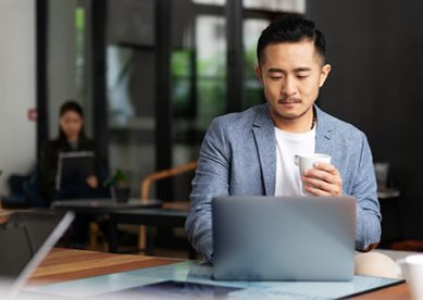 Young Businessman Working WIth Laptop Drinking Coffee