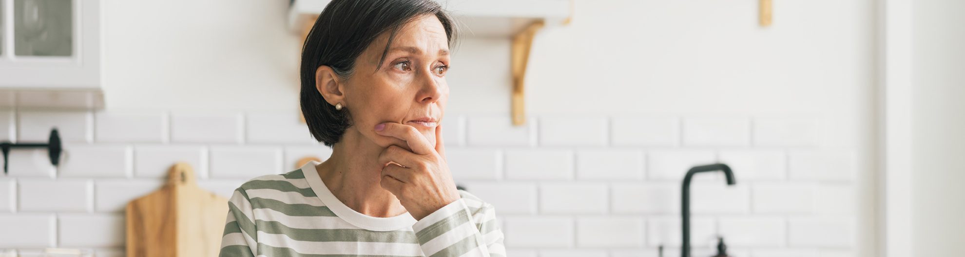 Women holding paper at kitchen table looking away