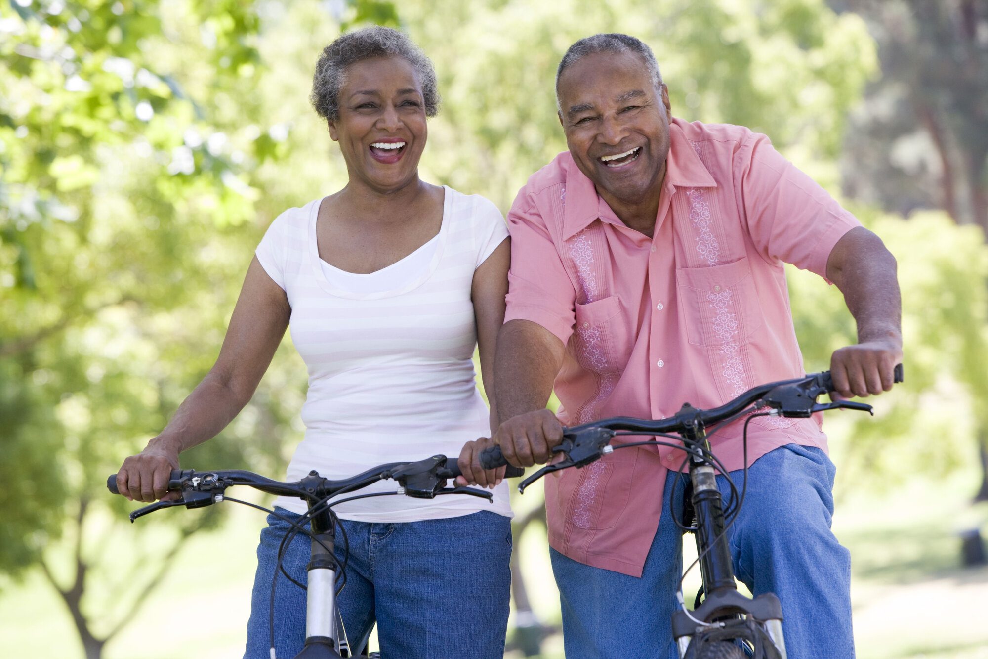 Older couple riding bikes on sunny day