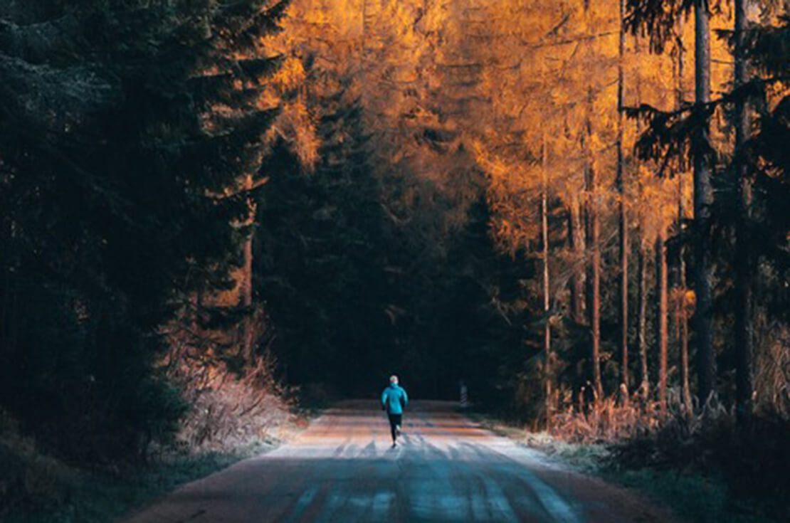 runner on road with trees on the side